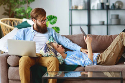 Pärchen mit Tablet und Computer auf dem Sofa.