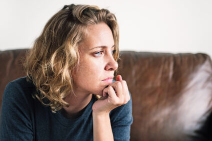 Frau mit ernstem Gesichtsausdruck auf einer Couch.
