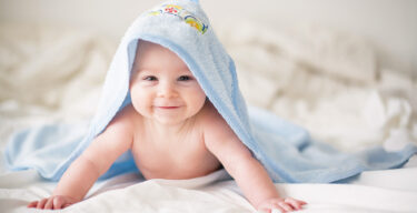 Ein glücklich lächelndes Baby unter einem Handtuch.
