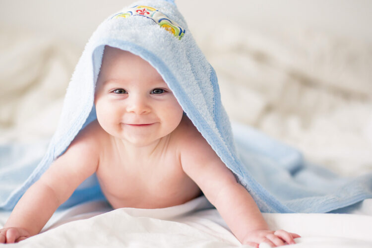 Ein glücklich lächelndes Baby unter einem Handtuch.