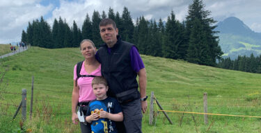 Jörg Schmitt mit seiner Frau und seinem Sohn beim Wandern vor grünen Wiesen.